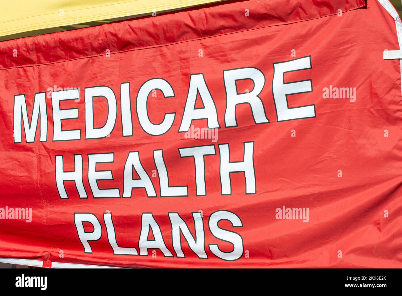 Ein großes rotes Stoffbanner mit medizinischen Gesundheitsplänen in weißer Schrift. Die Krankenhausversicherung medicare Gesundheitsplan Werbung in rot und weiß. Stockfoto