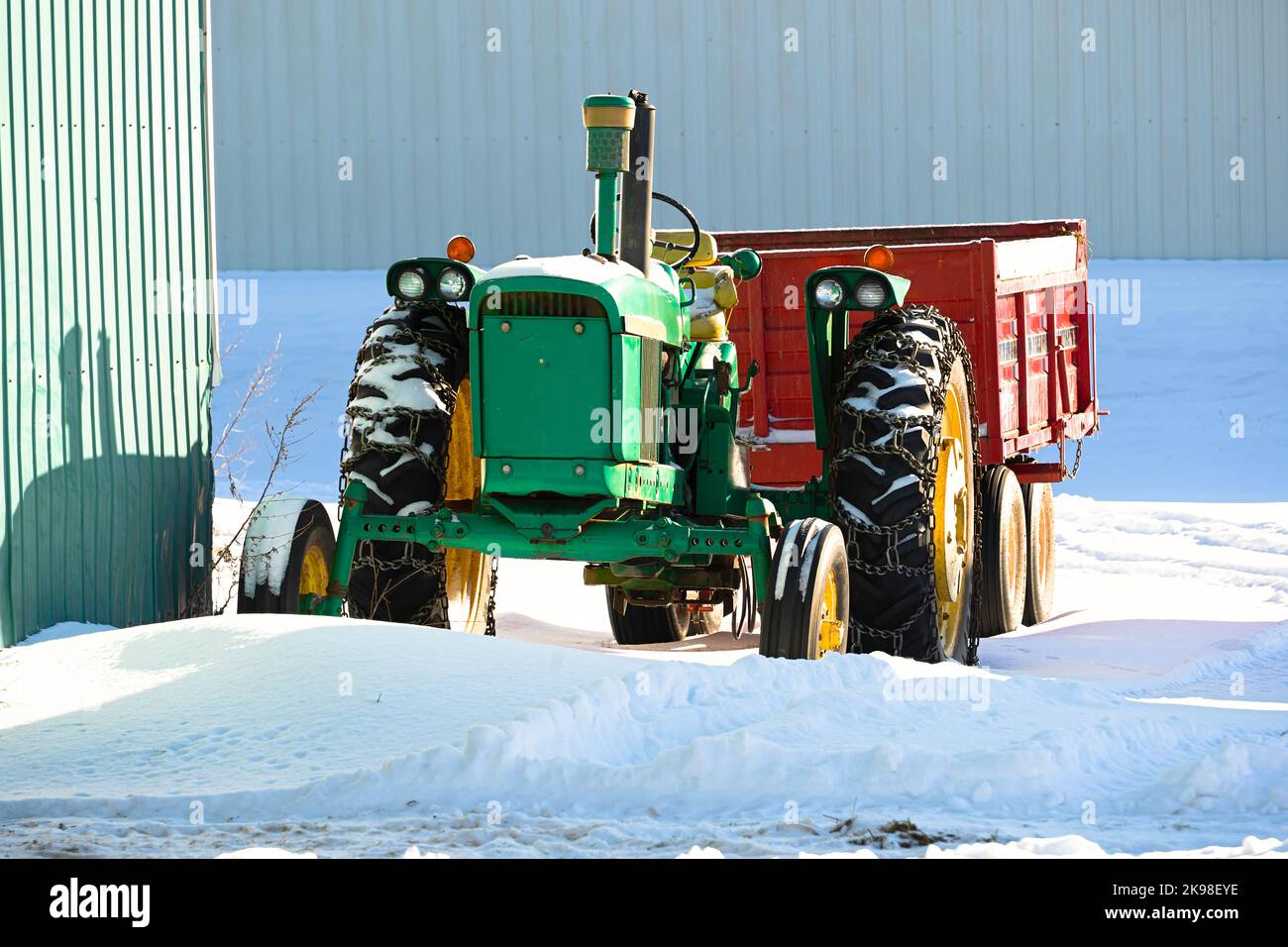 Alter Traktor und Wagen in einer Schneedecke. Stockfoto