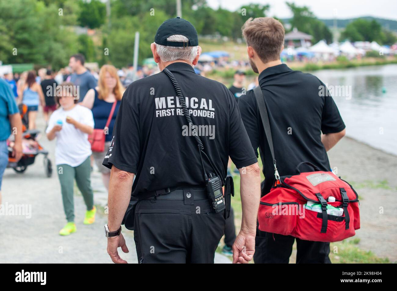 Medizinische Ersthelfer gehen in schwarzen Uniformen auf einer Straße entlang, wobei der medizinische Ersthelfer in grauen Buchstaben auf der Rückseite des Sanitäters steht. Stockfoto