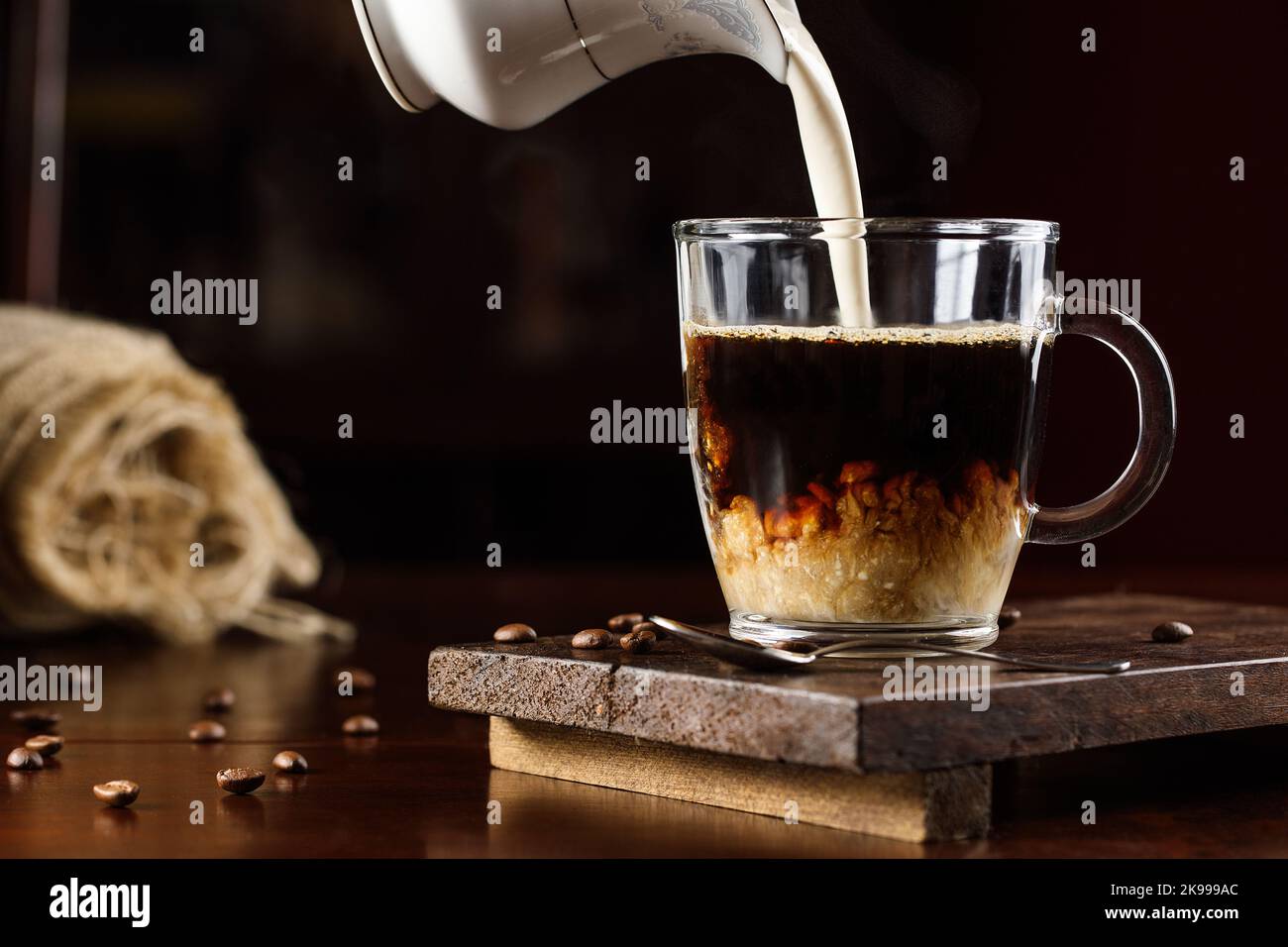 Milch wird auf den Kaffee gegossen Stockfoto