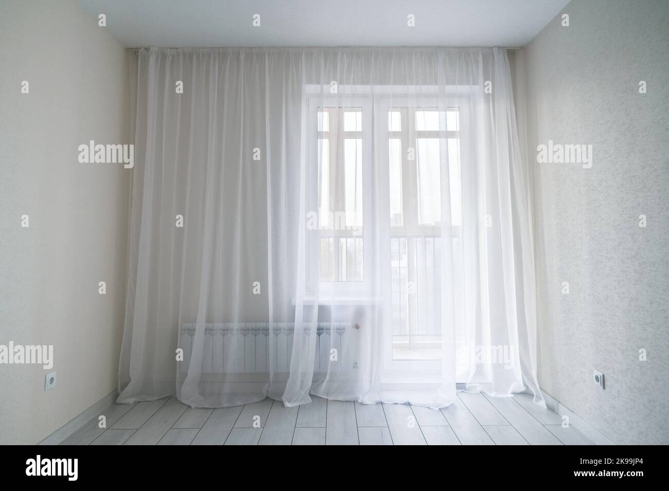 Weiße, leere, moderne Zimmereinrichtung mit Fenster und Balkon. Fenster im Hintergrund des kleinen, wirtschaftlichen Raums. Leeres Zimmer mit Fenster Stockfoto