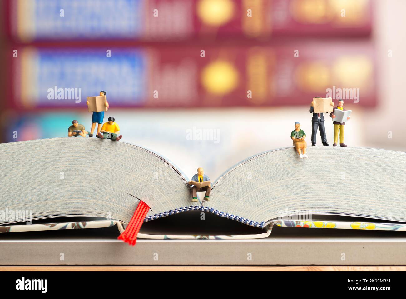 Nahaufnahme von Miniaturfiguren einer Gruppe von Menschen, die Buch und Zeitung lesen. Stockfoto
