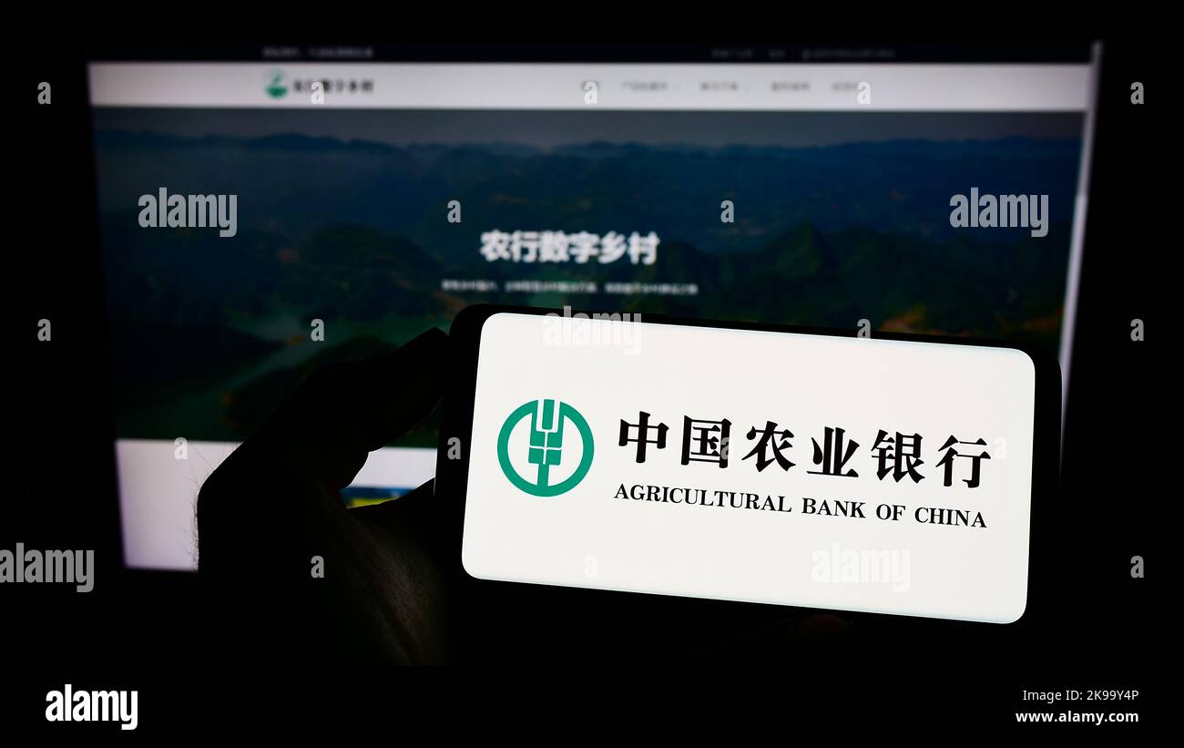Person hält Handy mit Logo der chinesischen Firma Agricultural Bank of China auf dem Bildschirm vor der Webseite. Konzentrieren Sie sich auf die Telefonanzeige. Stockfoto