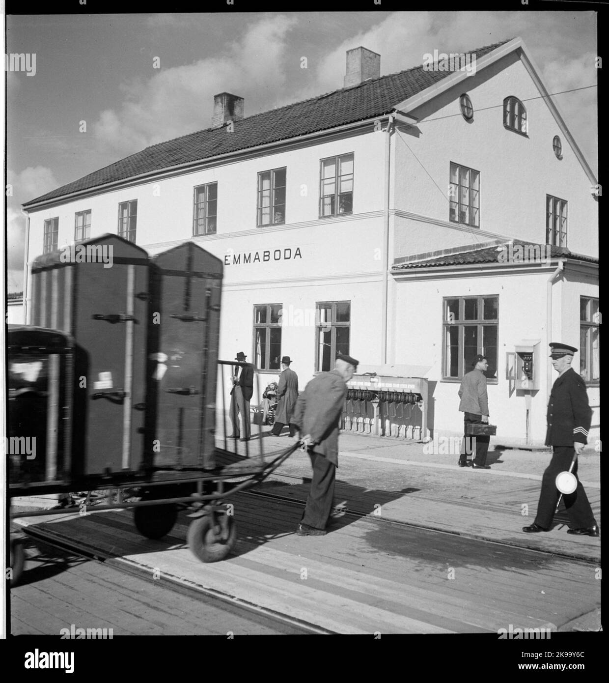 Das Personal zieht Kärra mit Gepäck über die Bahnstrecke in Emmaboda. Stockfoto