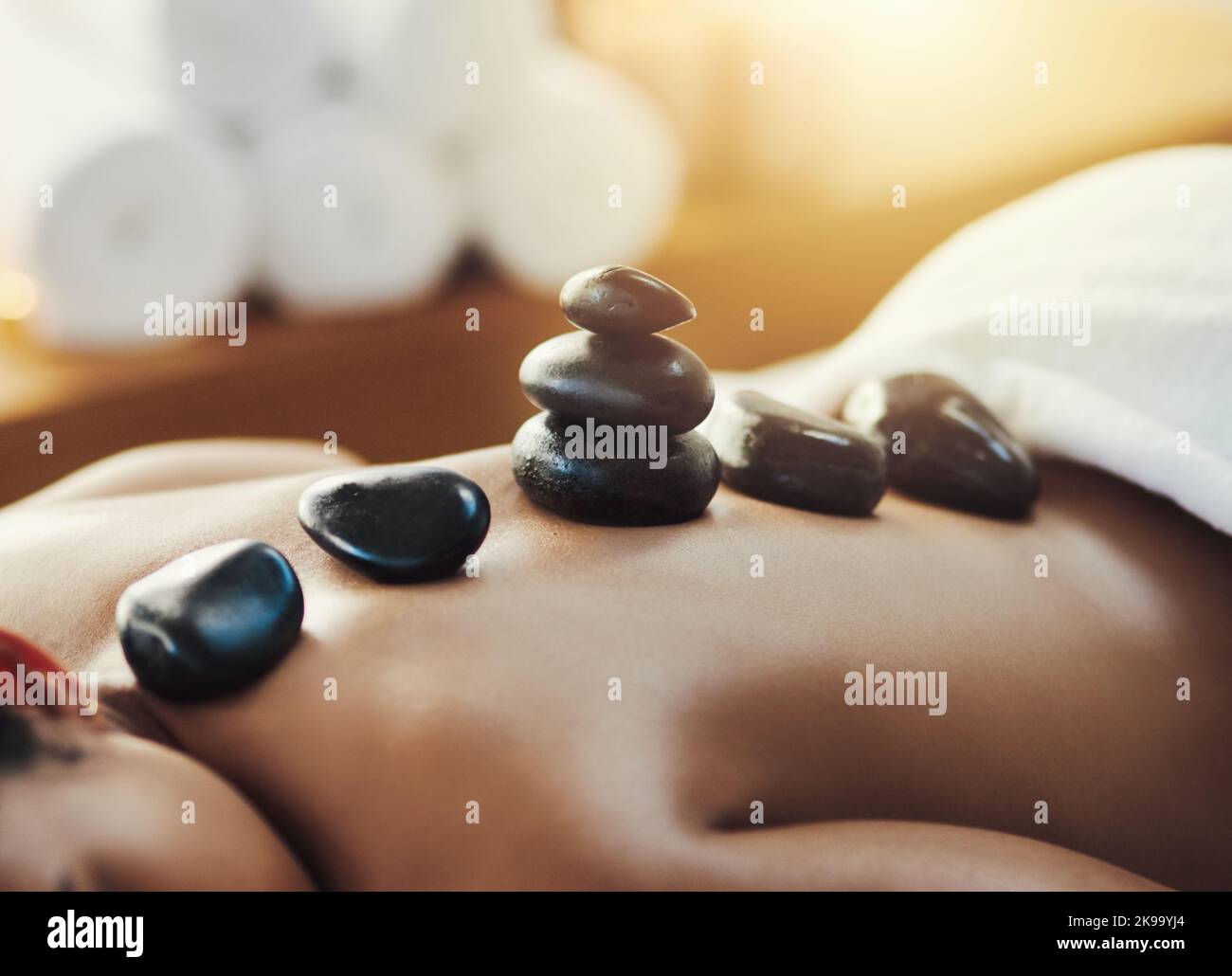 Mit einem Besuch im Spa können Sie Ihr Leben wieder ins Gleichgewicht bringen. Nahaufnahme einer Frau, die in einem Spa eine Hot Stone Massage bekommt. Stockfoto