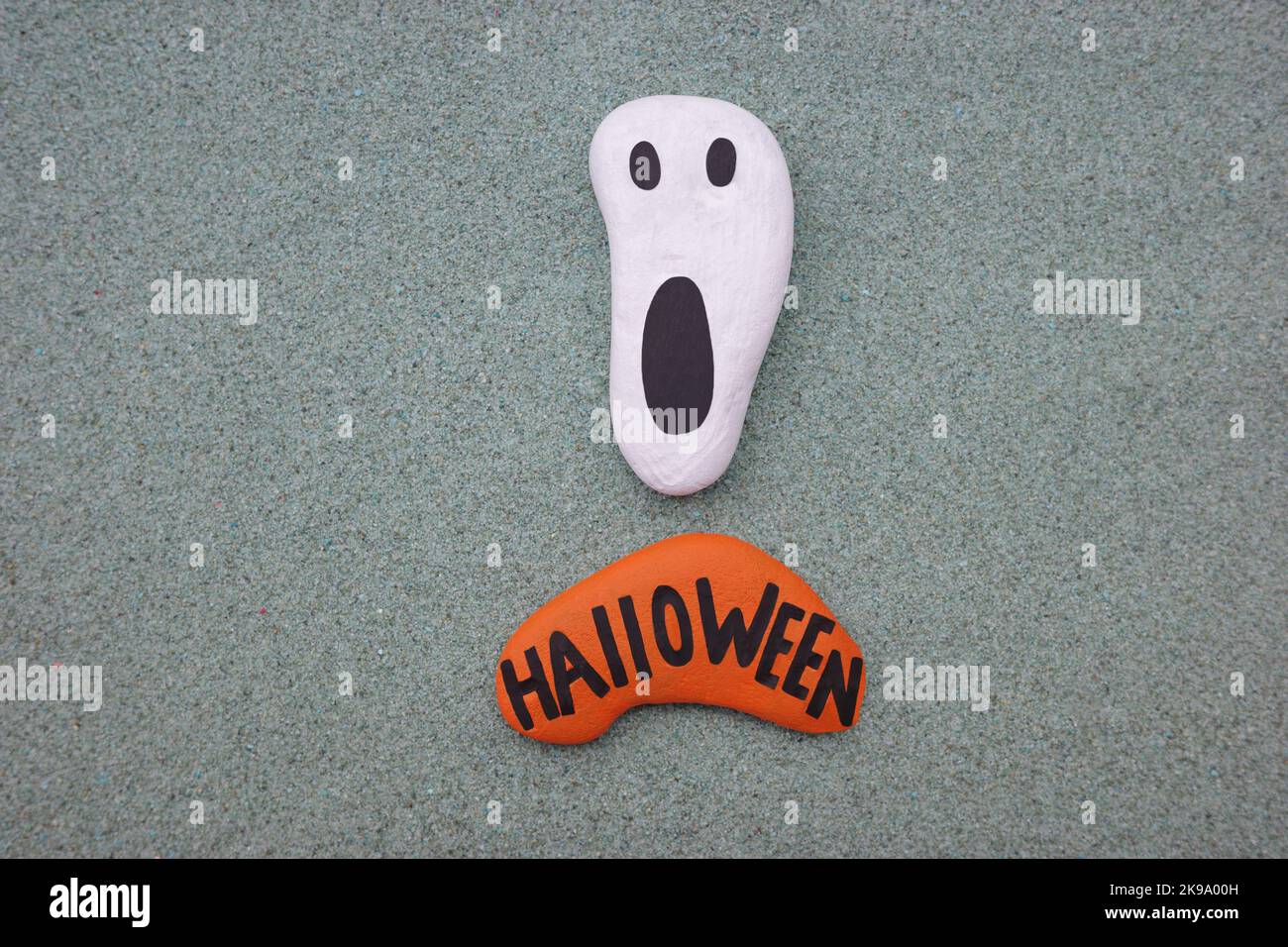 Halloween-Kunstwerke mit einem handbemalten Steingeist über grünem Sand Stockfoto