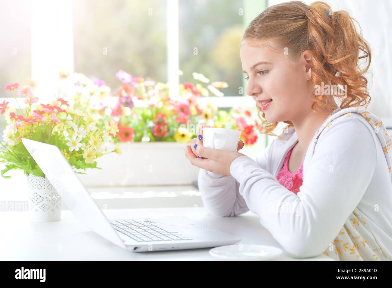 Teenager-Mädchen, das mit einem Laptop an einem Tisch sitzt Stockfoto