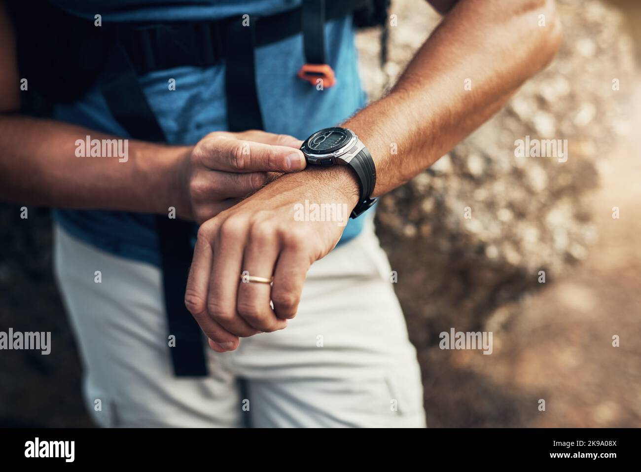 Oh lieber Blick auf die Zeit. Ein unkennbarer Mann, der seine Armbanduhr konfiguriert, während er auf eine Wanderung auf einen Berg geht. Stockfoto
