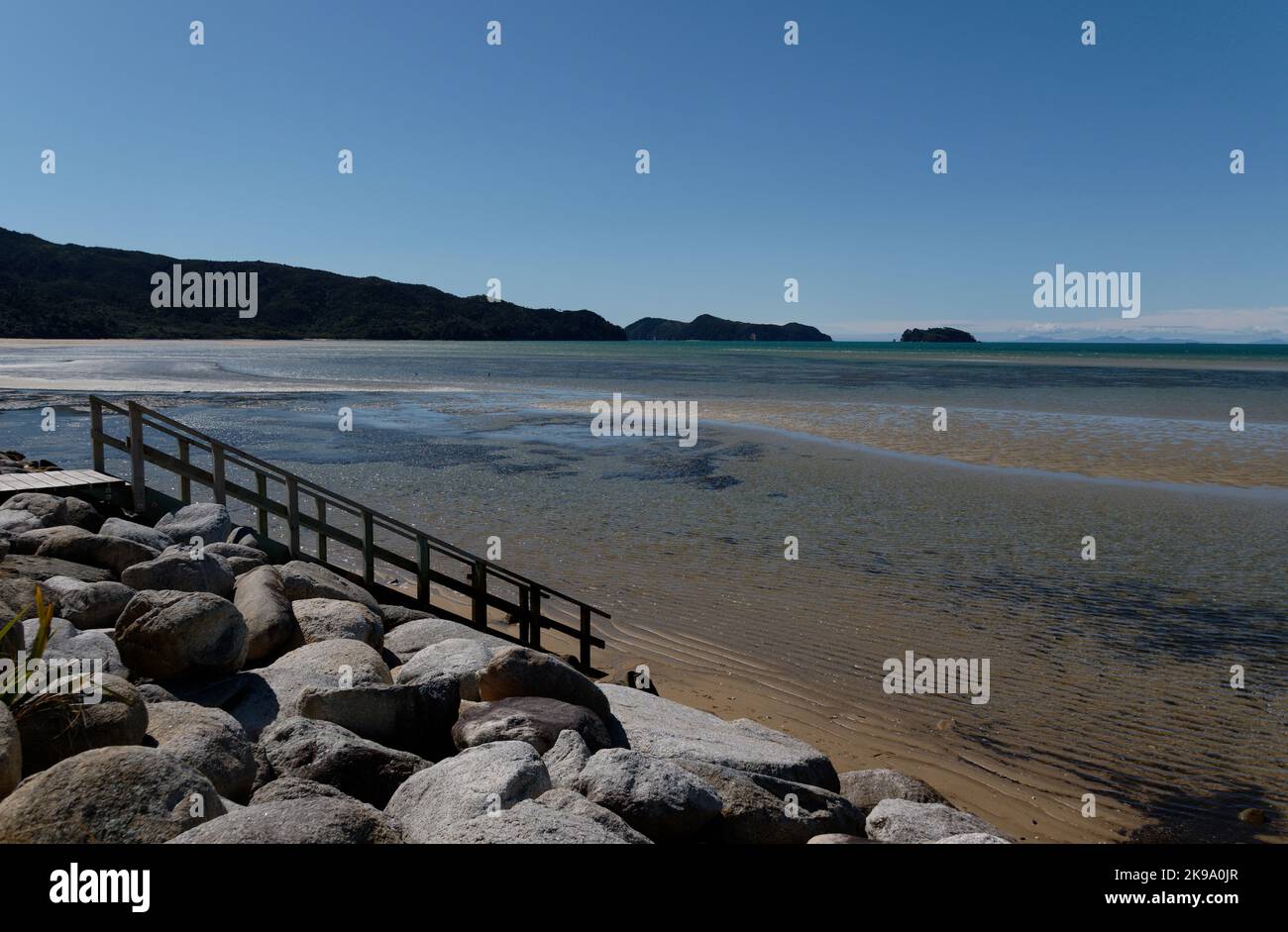 Das Meer rundt sanft an der Ufermauer in Marahau, dem Tor zu einem der Great Walks Neuseelands, dem Abel Tasman Coastal Track Stockfoto