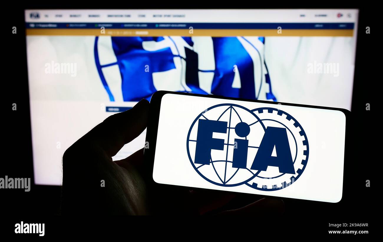 Person, die das Smartphone mit dem Logo der Internationalen Automobilföderation (FIA) auf dem Bildschirm vor der Website hält. Konzentrieren Sie sich auf die Telefonanzeige. Stockfoto