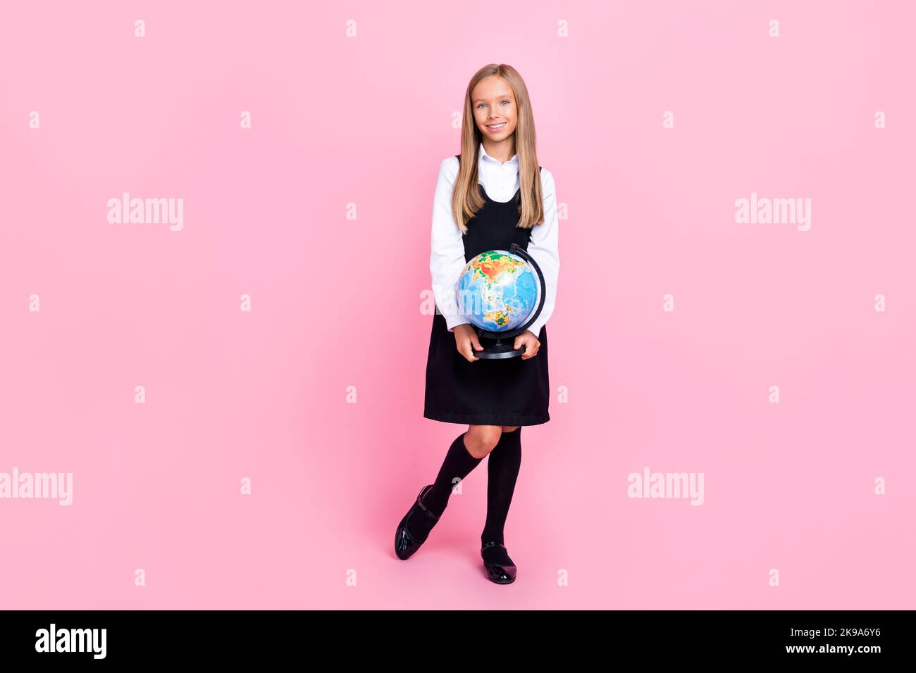 In voller Größe Foto von intelligenten gute Laune Mädchen gerade Frisur Schule uniform halten Globus Weltkarte isoliert auf rosa Hintergrund Stockfoto