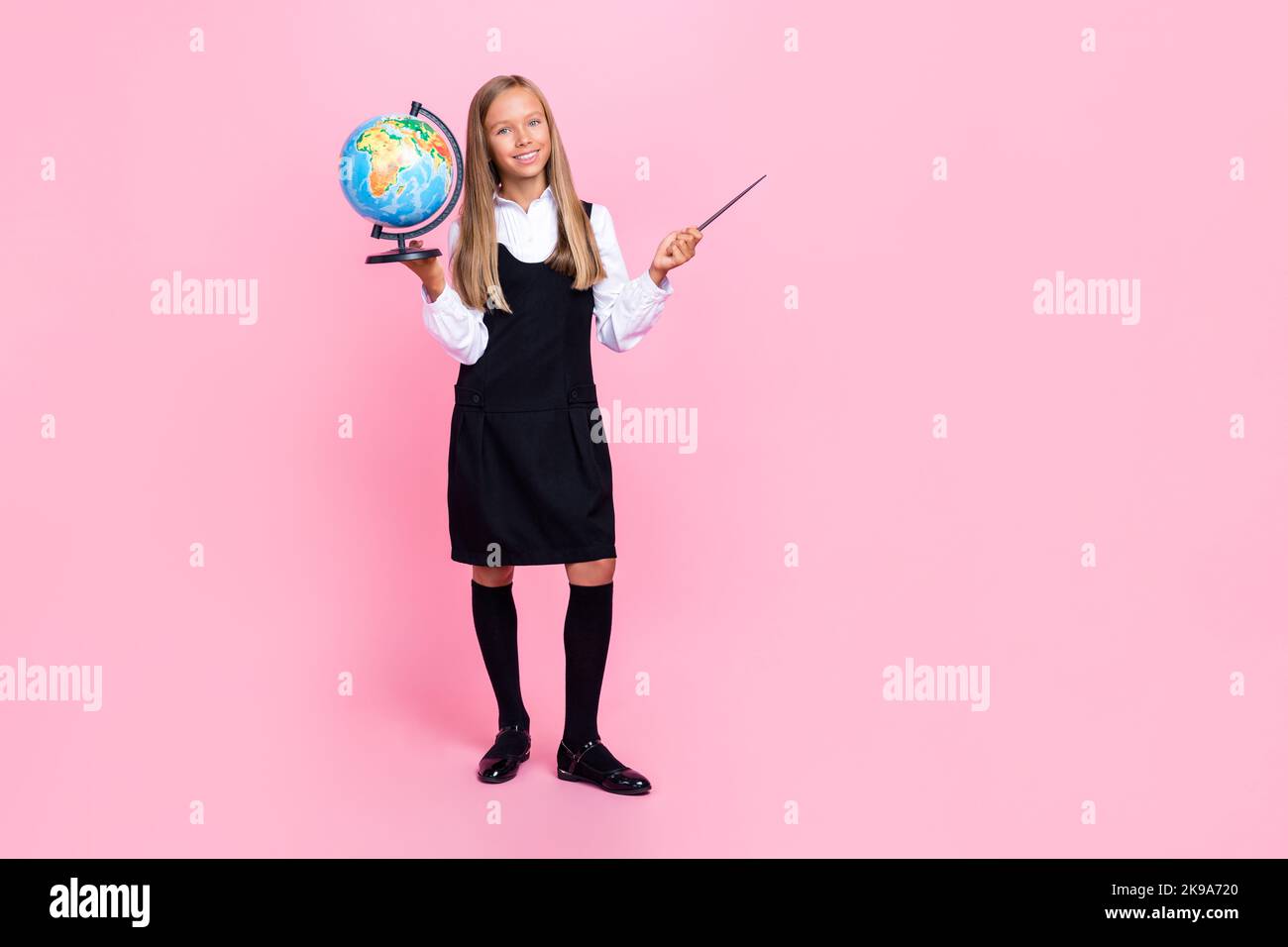 In voller Länge Foto von intelligenten Mädchen blonde Frisur Uniform halten Globus Zeiger richten leeren Raum isoliert auf rosa Hintergrund Stockfoto