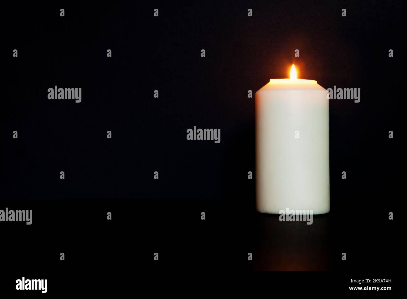 Weiße brennende Kerze auf schwarzem Hintergrund. Brennt in der Dunkelheit, kopieren Raum. Ewige Erinnerung, Trauer, Stockfoto