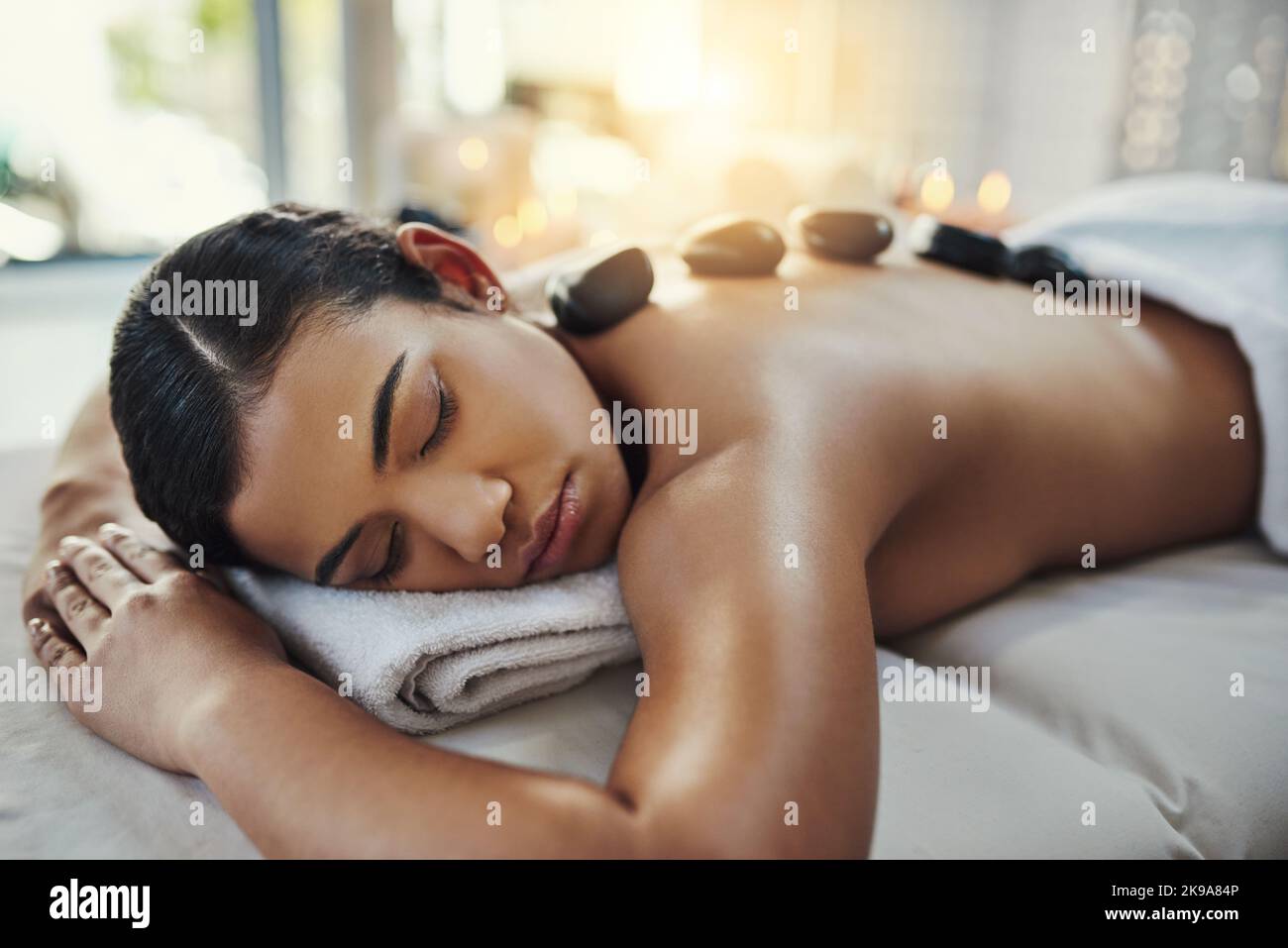 Heiße Steine haben eine beruhigende Wirkung, die tiefe Entspannung fördern kann. Eine junge Frau bekommt eine Hot-Stone-Massage in einem Spa. Stockfoto