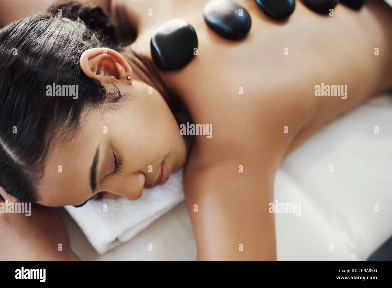 Mit Steinen den Alltagsstress lindern. Eine junge Frau bekommt eine Hot-Stone-Massage in einem Spa. Stockfoto