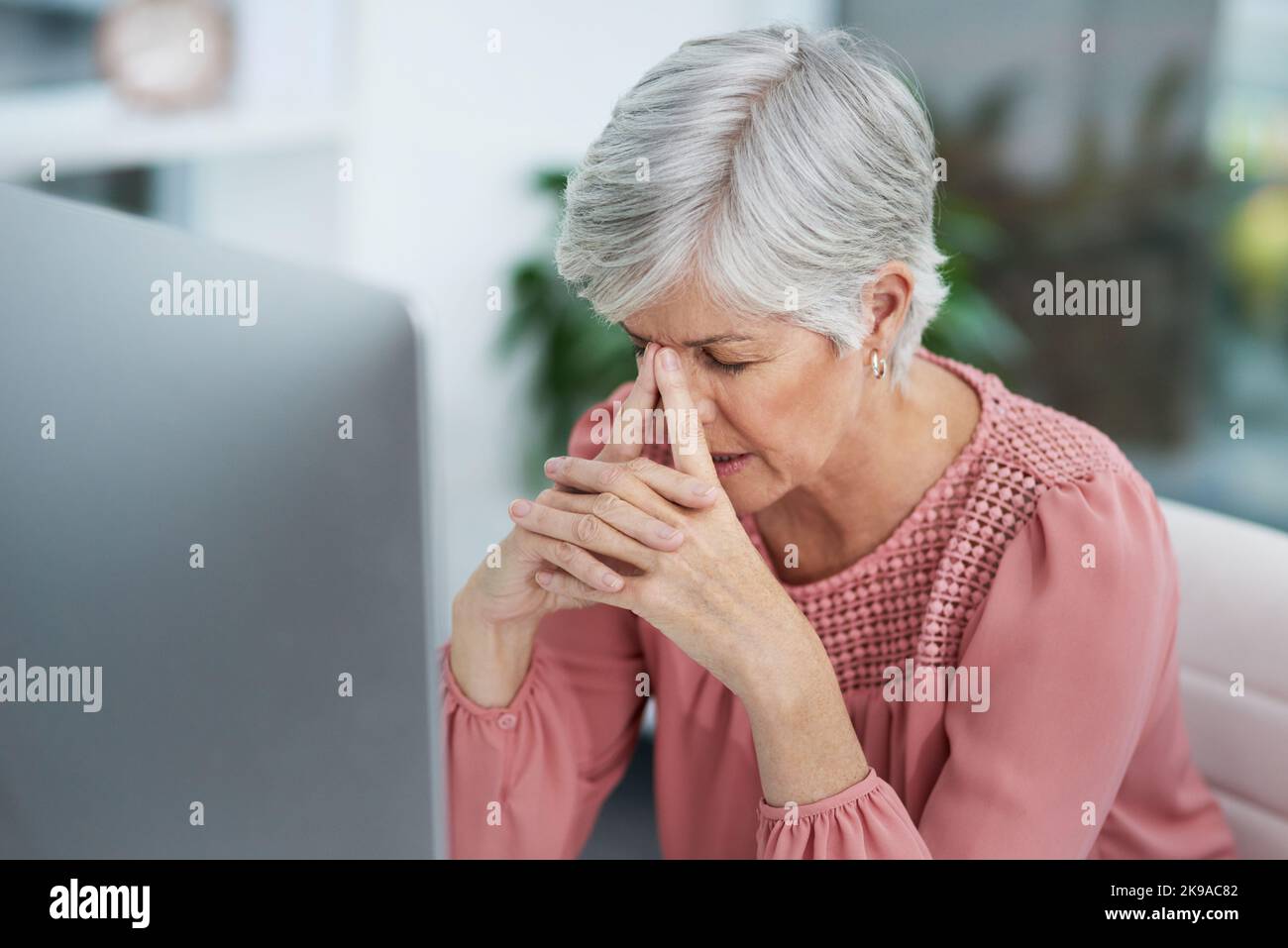 Ich kann nicht mit einer Lösung für diese kommen. Eine reife Frau, die gestresst in ihrem Büro bei der Arbeit aussieht. Stockfoto