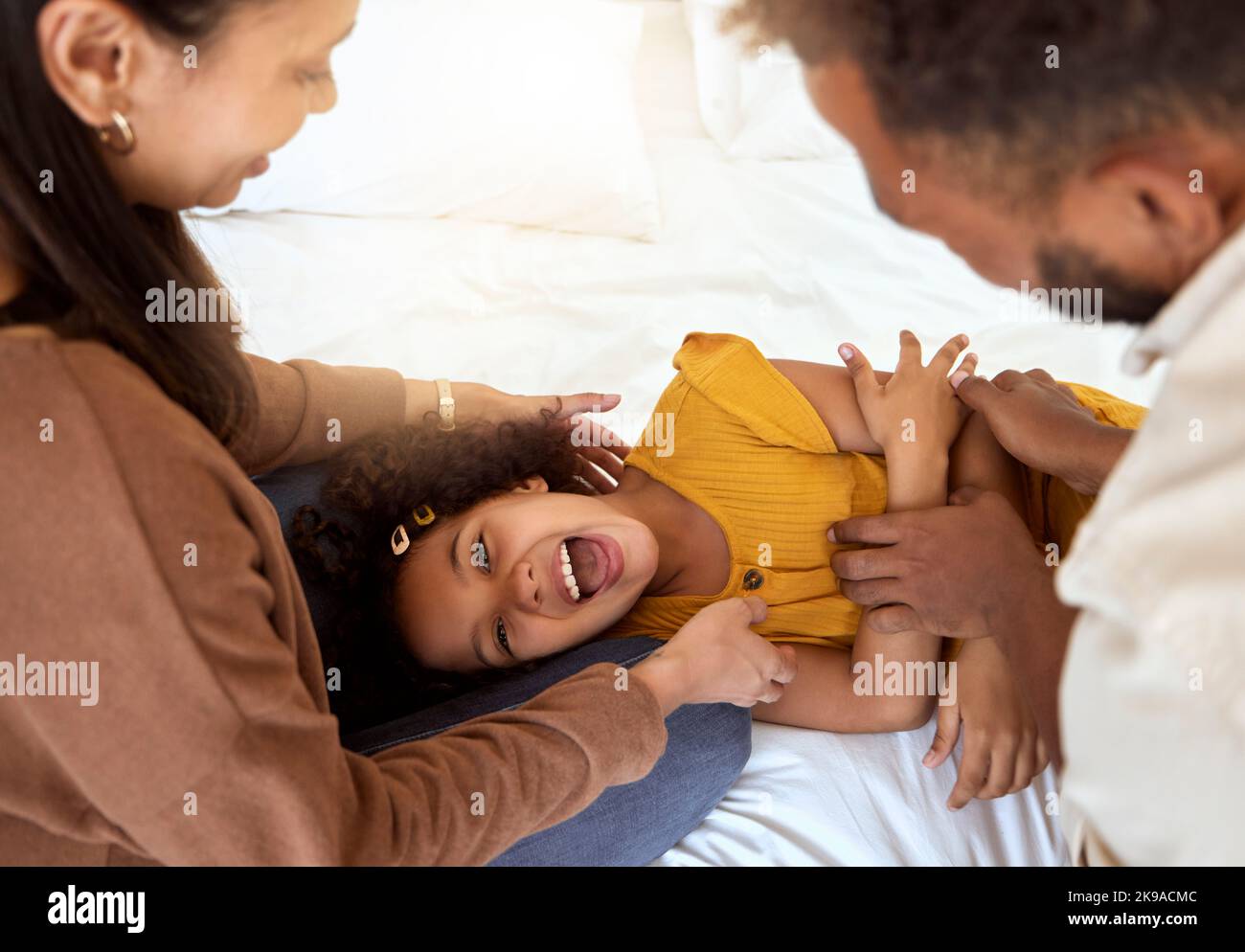 Familie kitzeln, spielen und Mädchen mit glücklichen Eltern verbinden sich mit viel Zeit zusammen zu Hause. Lachen, Lächeln und Glück eines Kindes lächeln mit Stockfoto