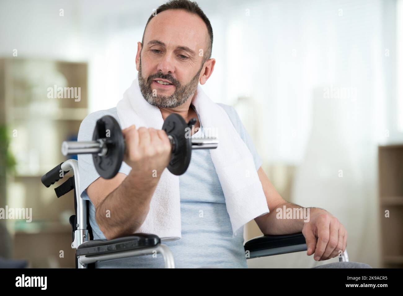 Mann im Rollstuhl, der Hanteln aufsteigt Stockfoto