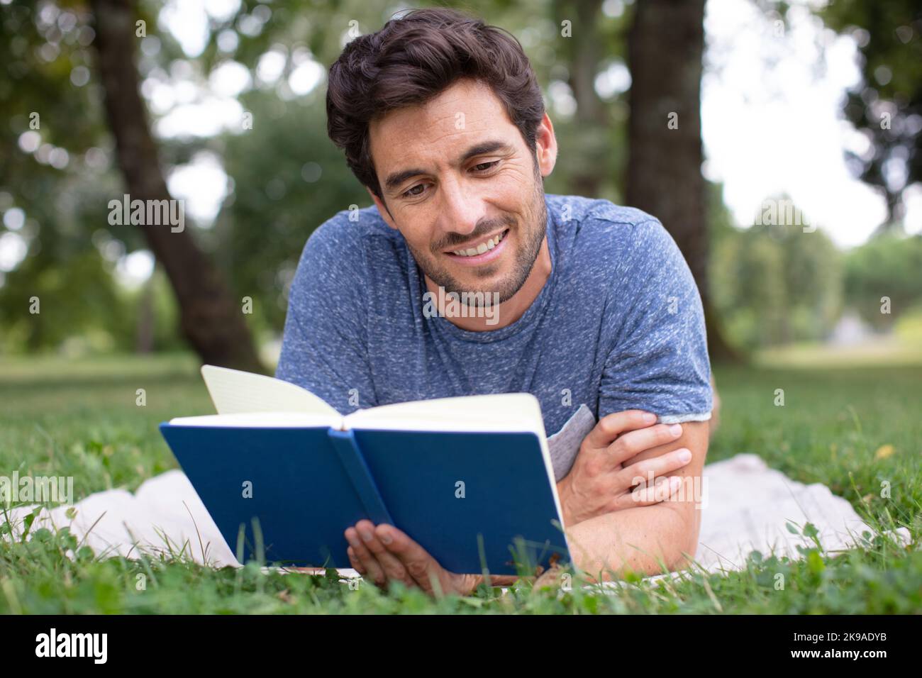 Mann in seinem späten 30s ein Buch im Park zu lesen Stockfoto