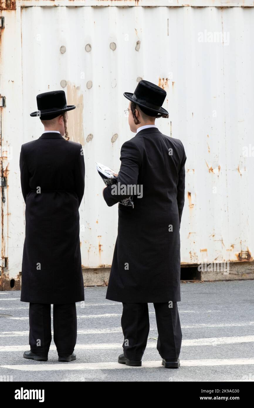 2 orthodoxe jüdische Jungen unterhalten sich, während sie darauf warten, eine Straße zu überqueren. In Brooklyn, Neew York. Stockfoto