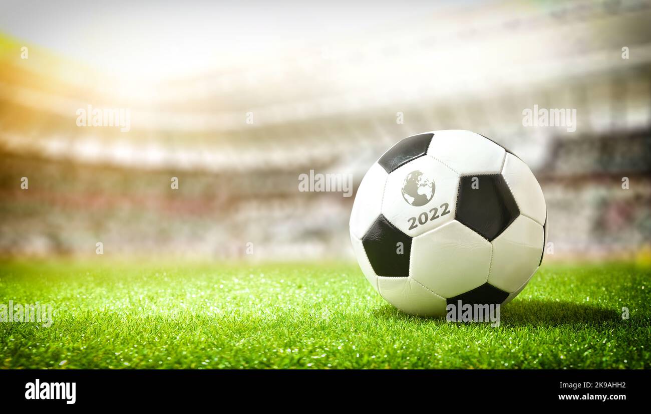 Detail eines Balls auf dem Rasen eines Fußballstadions, der das Weltcup-Turnier 2022 ankündigt. Stockfoto