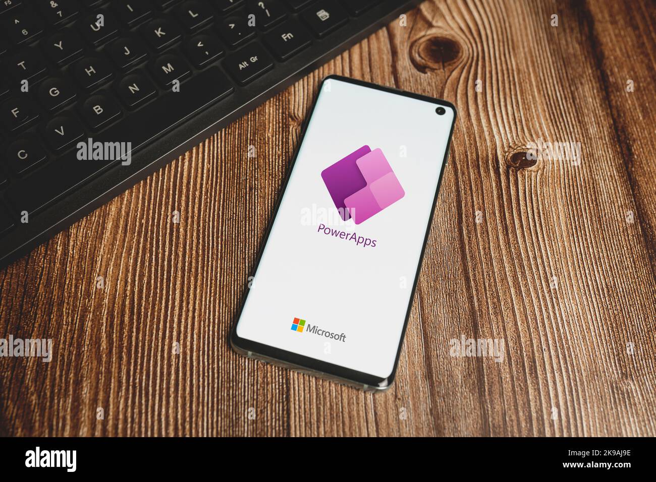 Microsoft Power Apps-Logo und schwarze Tastatur auf Holzhintergrund. Swansea, Großbritannien - 24. Oktober 2022. Stockfoto