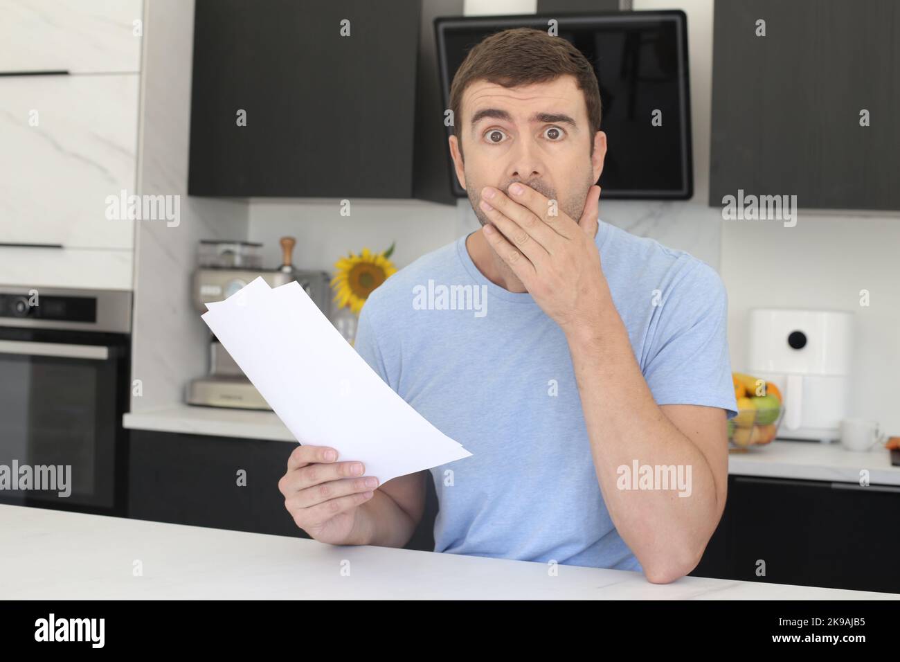 Gestresster Mann, der in der Küche nach Dokumenten sucht Stockfoto