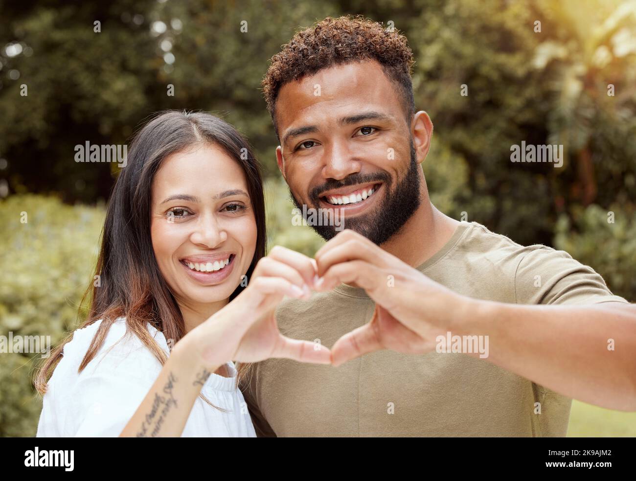 Paar, glücklich und Hand Herz Zeichen in einem Naturpark zeigt Liebe und ein Lächeln im Freien. Schwarze Menschen mit Glück und Sorgfalt, die Hände zusammen zu setzen Stockfoto