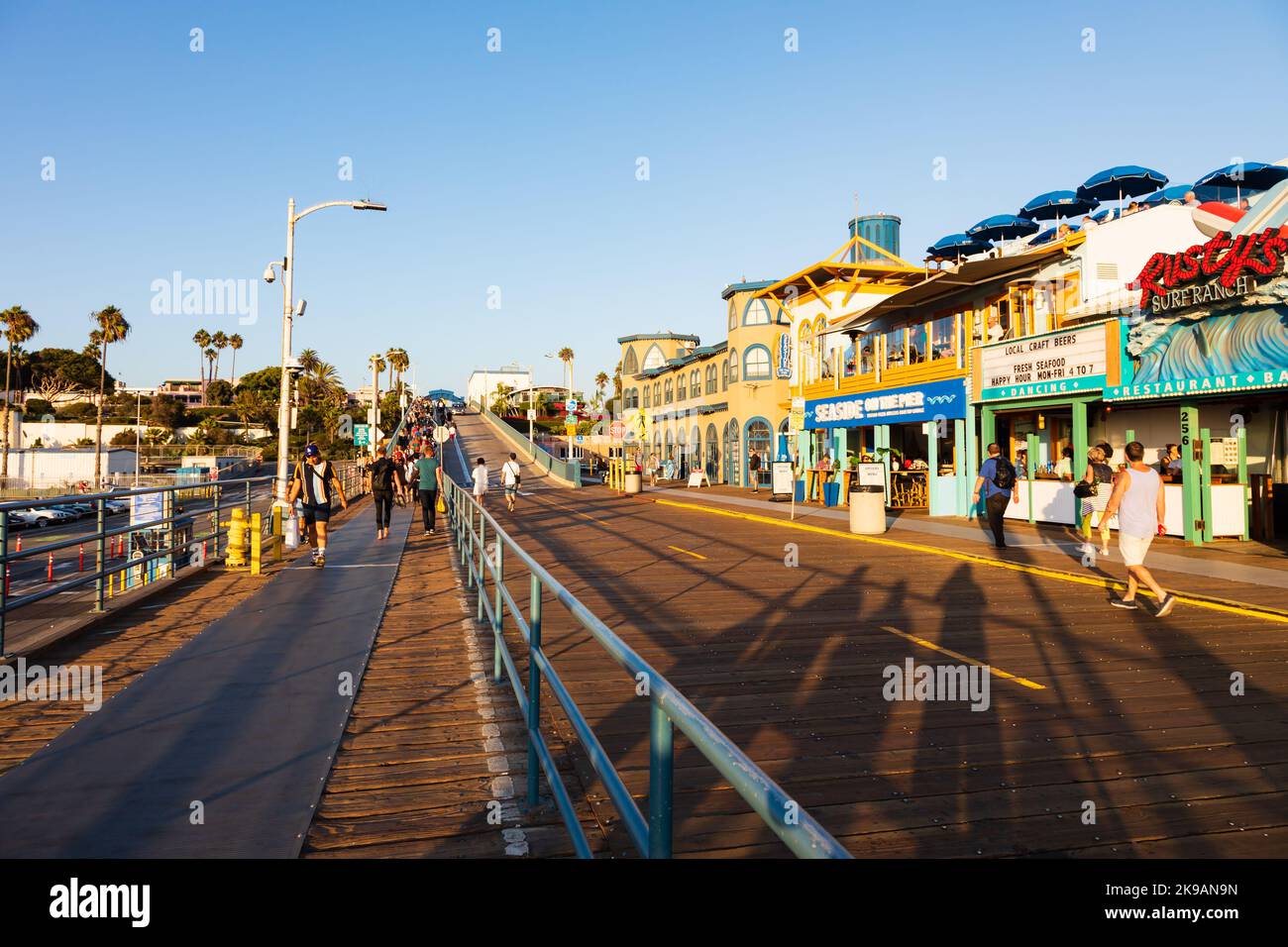Touristen schlendern am Santa Monica Pier entlang, wenn die Sonne untergeht. Kalifornien, USA Stockfoto