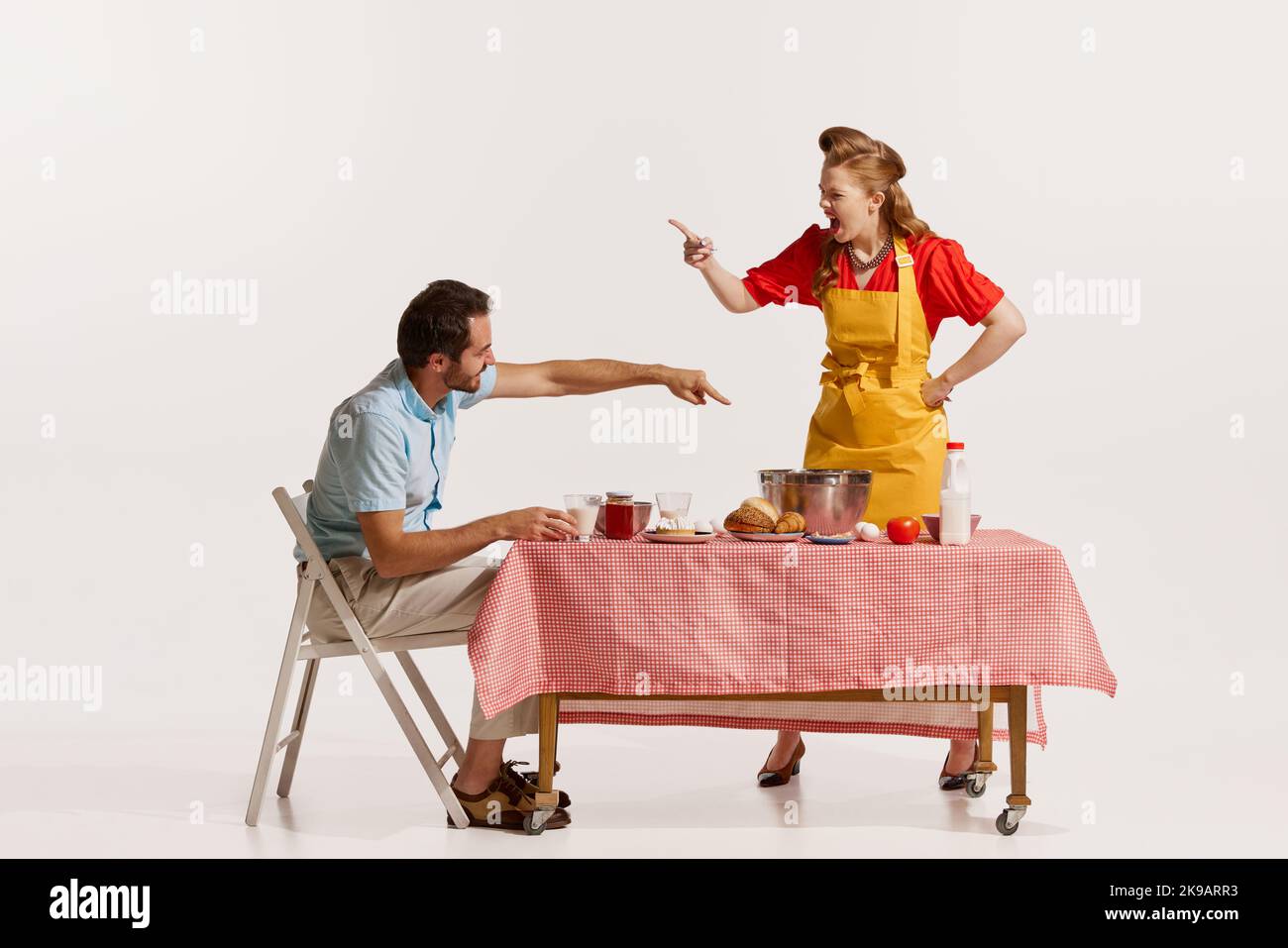 Porträt eines jungen gefühlvollen Paares streitet, während das Frühstück isoliert auf weißem Hintergrund Stockfoto