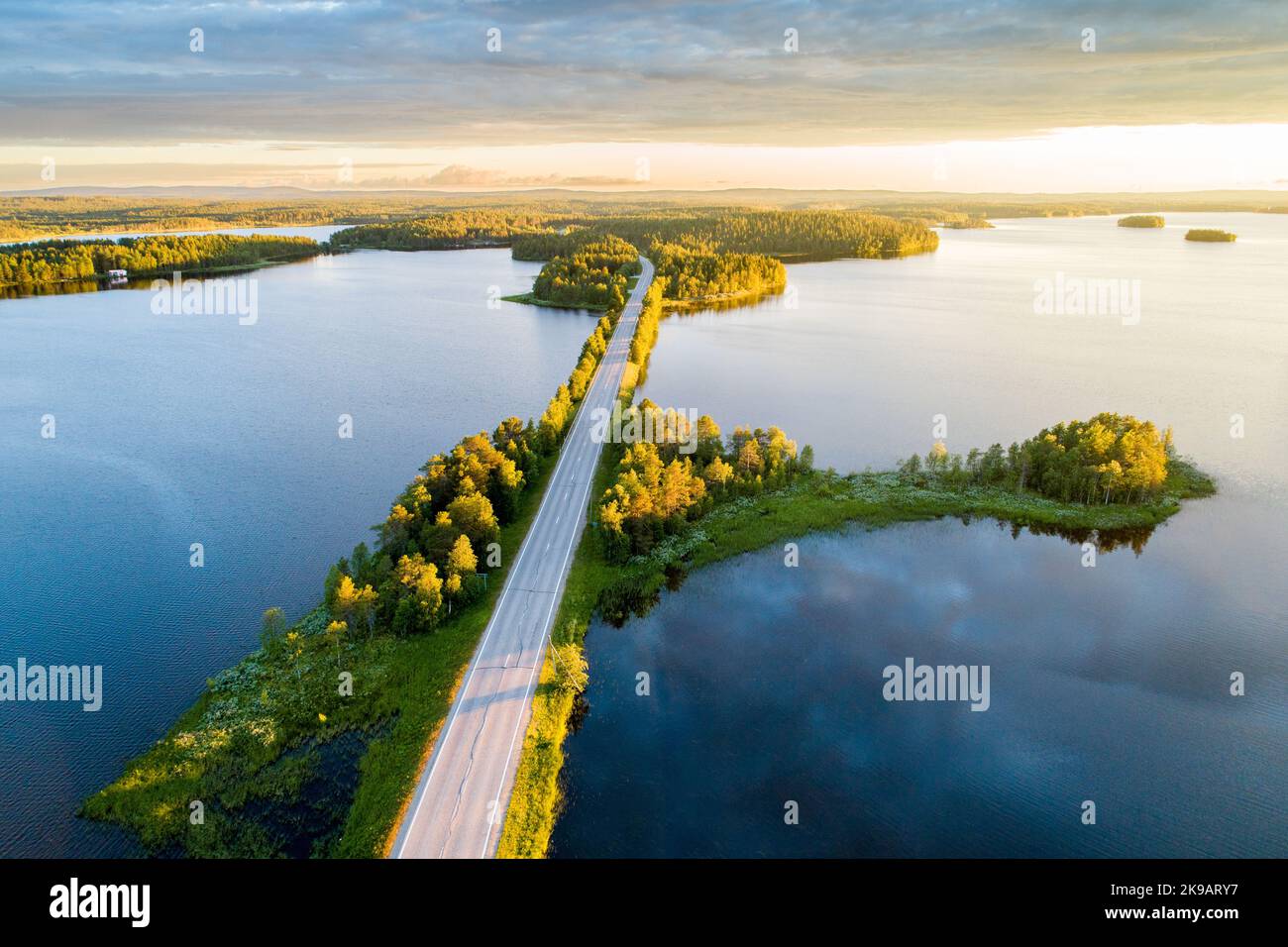 Straße inmitten der Seenlandschaft während eines wunderschönen sommerlichen Sonnenuntergangs in Nordfinnland Stockfoto