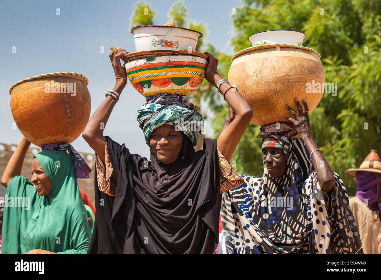 Afrikanische Stämme, Nigeria, Borno State, Maiduguri Stadt. Weibliche Mitglieder des Fulani-Stammes in farbenfroher Kleidung tragen sie Schiffe mit Wasser auf ihren Köpfen Stockfoto