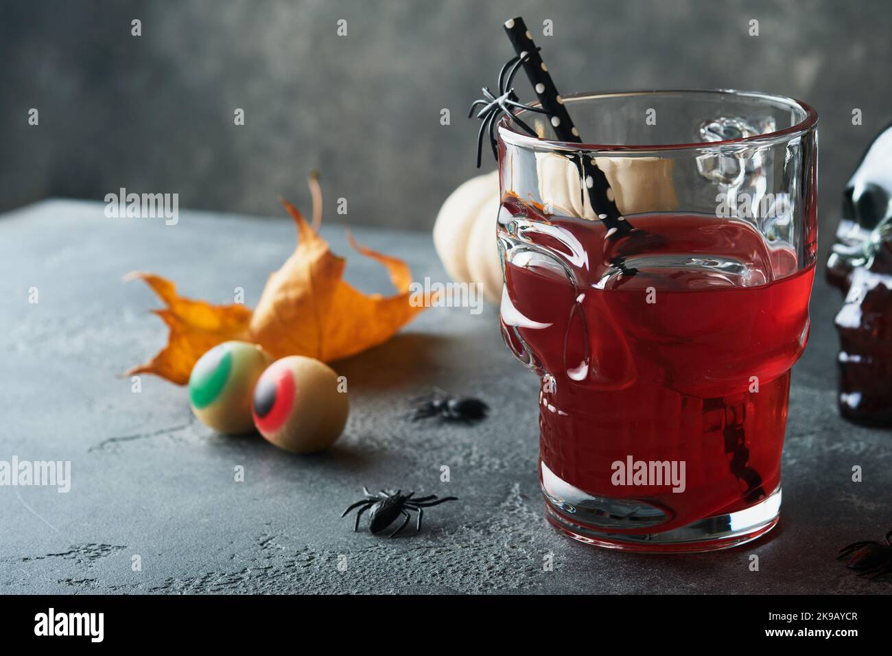 Blutiger Halloween-Cocktail. Blutig roter Cocktailglas-Becher für Halloween und Flaschenform Totenkopf auf dunklen Hintergründen. Halloween-Party mit Süßigkeiten Augen, Stockfoto