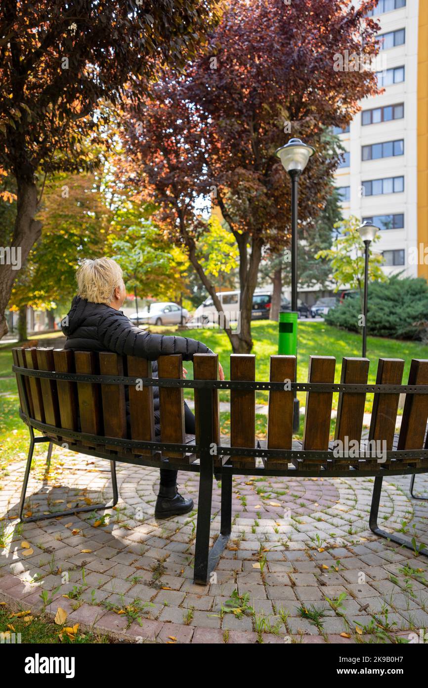 Frau, die im Herbst im Park sitzt Stockfoto