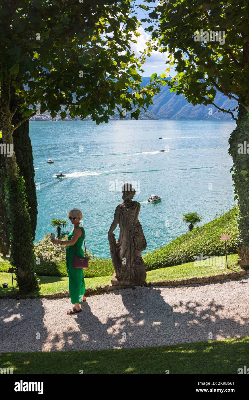 Weiblicher Tourismus, Blick im Sommer auf eine Frau, die ein Foto von sich selbst vor dem Hintergrund des Comer Sees, Lombardei, Italien, macht Stockfoto