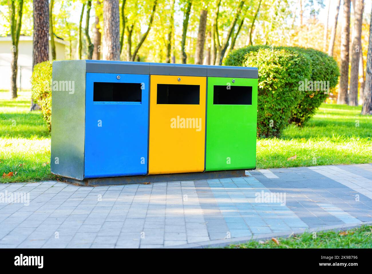 Farbige Mülltonnen für die Sammlung und Sortierung von Abfällen in einem öffentlichen Park an einem sonnigen Tag. Abfallrecycling-Konzept. Stockfoto