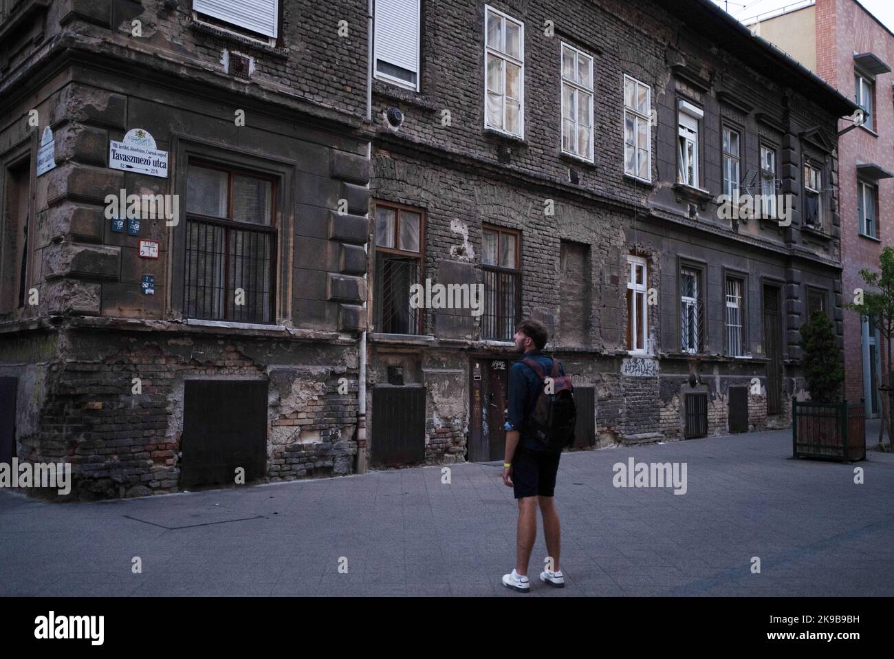 Mann, der auf ein altes Wohnhaus mit zerfallenden Wänden schaut Stockfoto