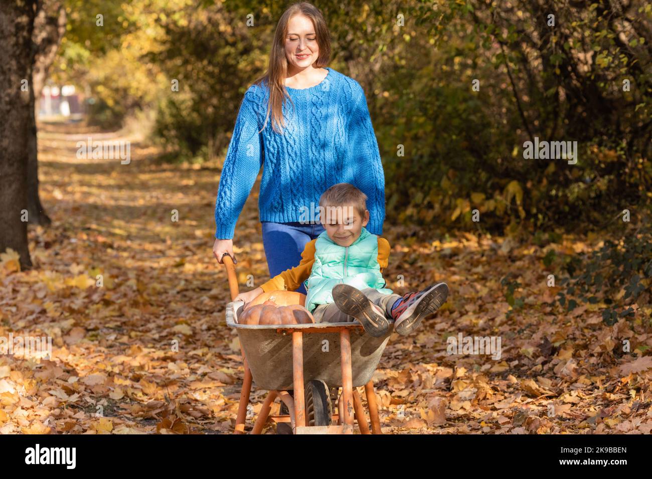 Mutter haben Spaß mit Kind, verwenden Sie Garten Schubkarre mit Kürbissen Stockfoto