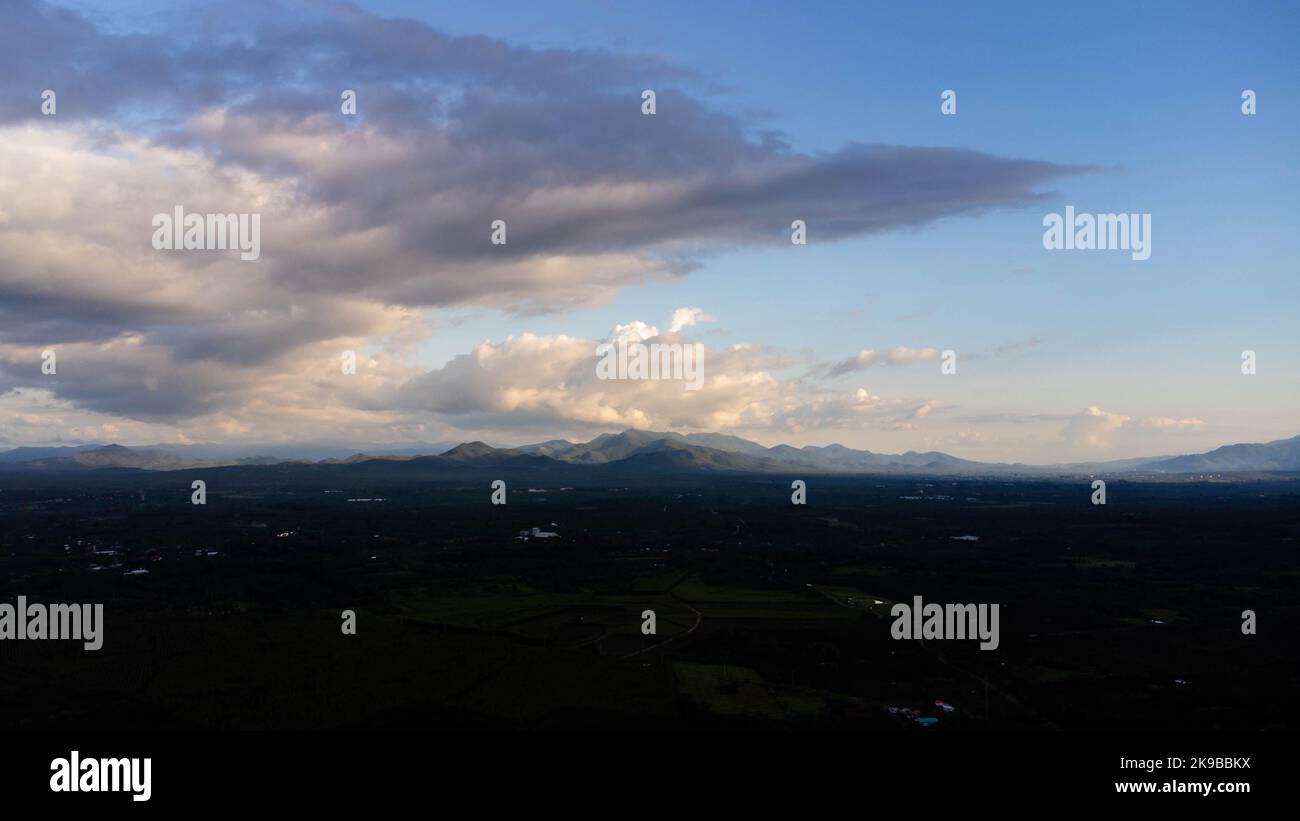 Zeitraffer von schönen Himmel mit Wolken und Sonnenlicht während des Sonnenuntergangs vor dem Hintergrund der Silhouetten von Berglandschaften und ländlichen Dörfern. na Stockfoto