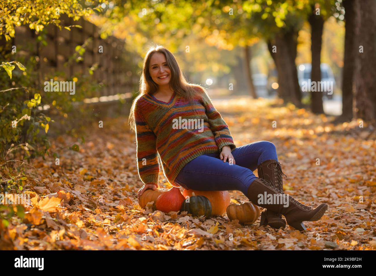 Lächeln Frau sitzt auf dem Kürbis auf den Autuman Ahornblätter Stockfoto