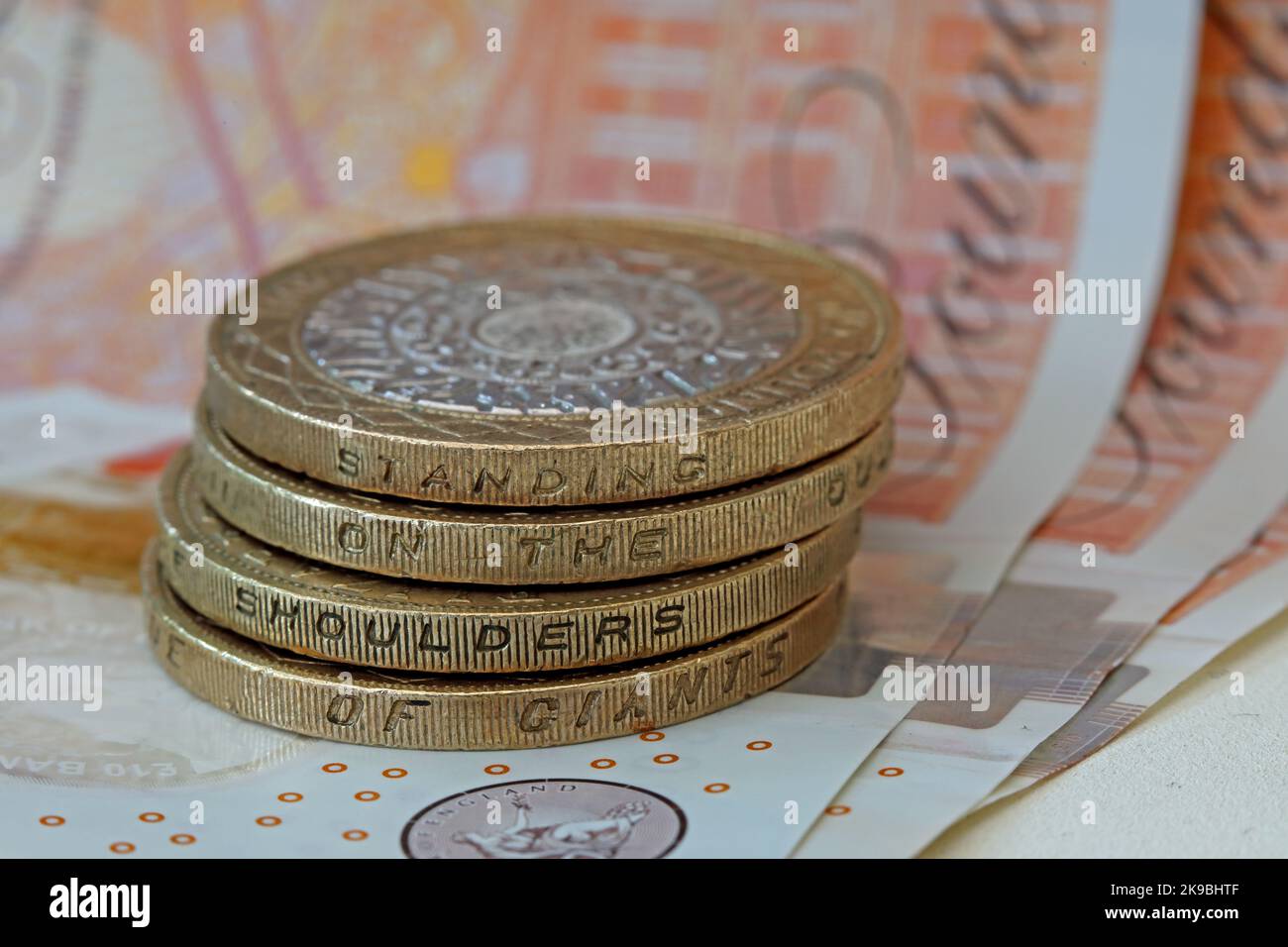 Bank of England, Sterling Banknoten, mit zwei Pfund-Münzen mit der Aufschrift „auf den Schultern der Riesen stehen“. Münzen und Bargeld in harter Währung notieren Stockfoto
