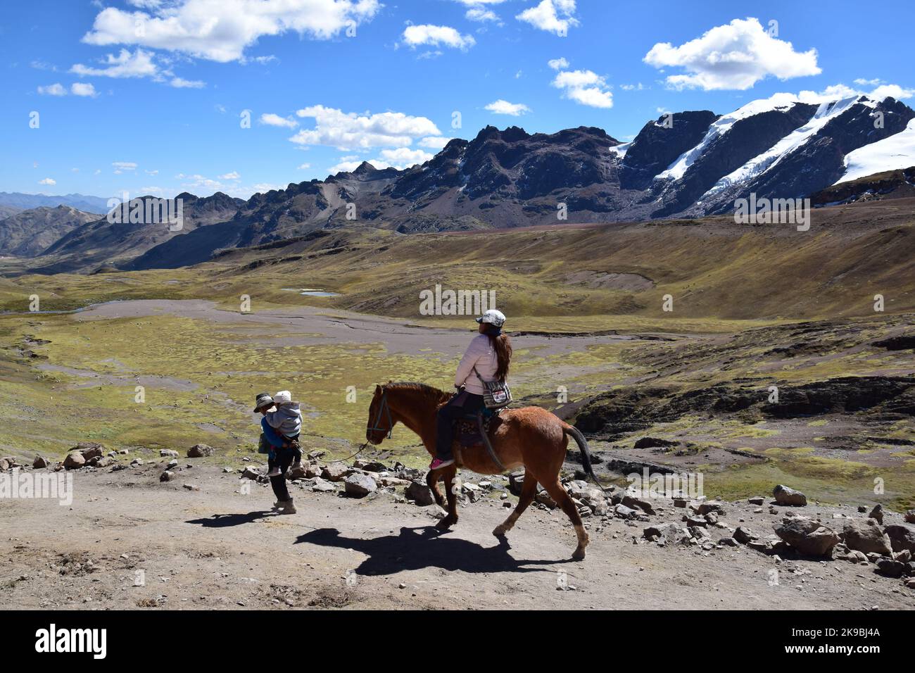 Einheimische in traditioneller Kleidung, die mit seinem Pferd den Hügel in der Nähe der Bergkette Vilcanota in der Region Cusco, Peru, hinaufgehen Stockfoto