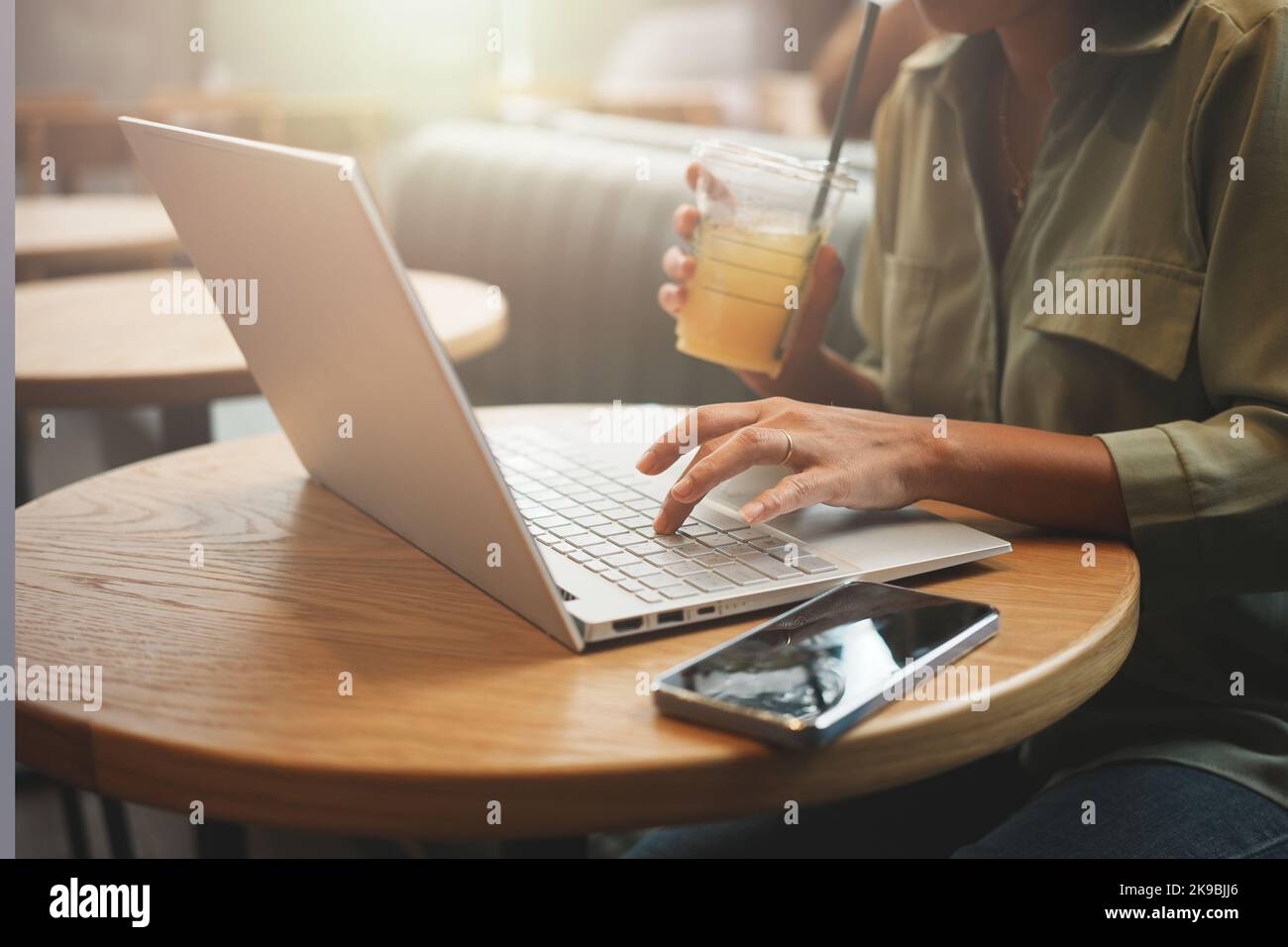 Frau, die mit einem Laptop arbeitete und Orangensaft im Café trank. Stockfoto