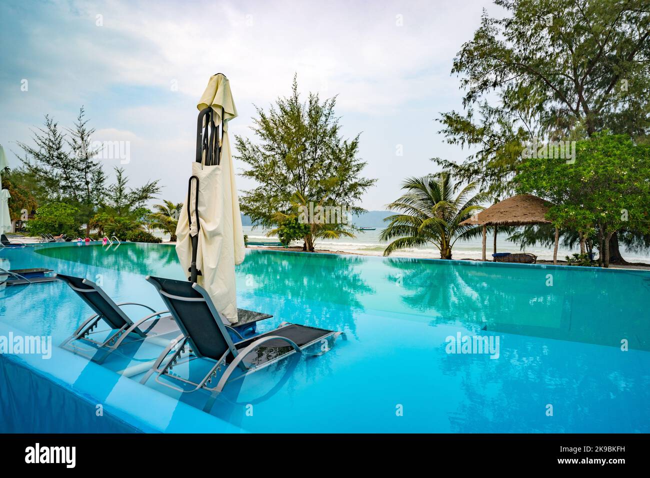 Im Pool am Strand befinden sich zwei Liegestühle in klarem Wasser. Außenpool mit wunderschönem Meerblick. Das Konzept des Luxusaufenthalts. Stockfoto