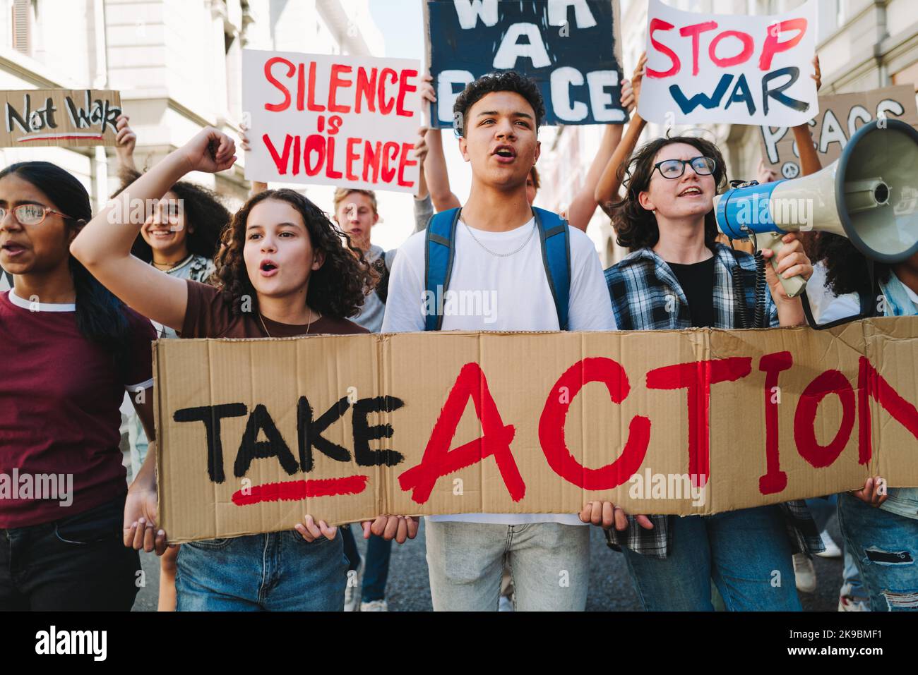 Jugendaktivismus für Frieden und Menschenrechte. Eine Gruppe multikultureller Friedensaktivisten marschiert mit Plakaten und Spruchbändern auf die Straßen. Vielfältige junge Menschen Stockfoto