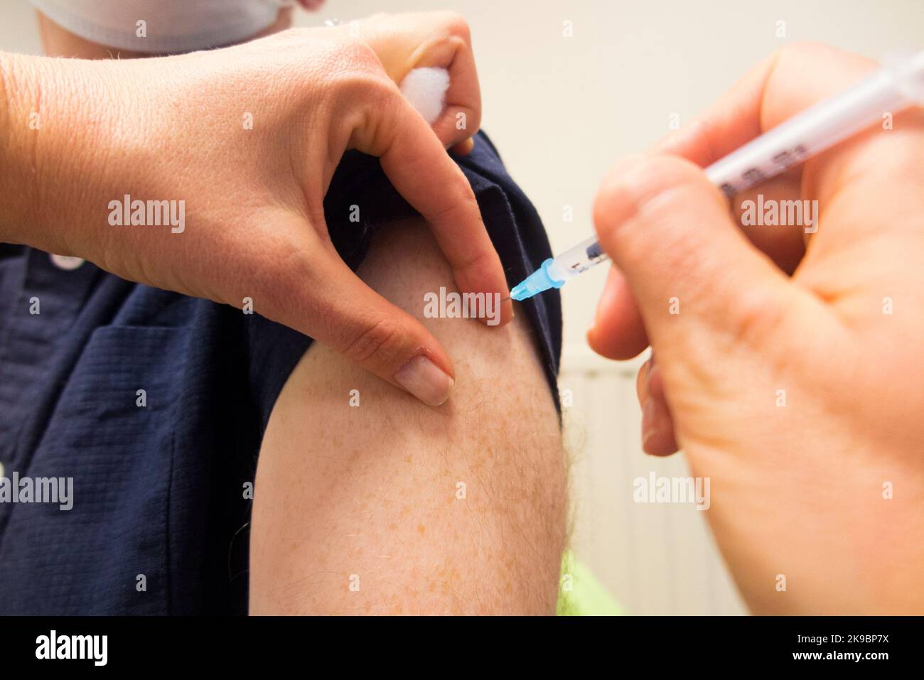 Mann im Alter von 59 Jahren (Model released) erhält den Impfstoff-Booster Pfizer COVID-19, um die Immunität zu verbessern und ihn gegen eine Infektion mit omicron Delta oder anderen vorhandenen Coronaviren einzuimpfen. Die Praxiskrankenschwester verwaltet die Injektion bei der örtlichen Hausarztpraxis in Twickenham. VEREINIGTES KÖNIGREICH (132) Stockfoto
