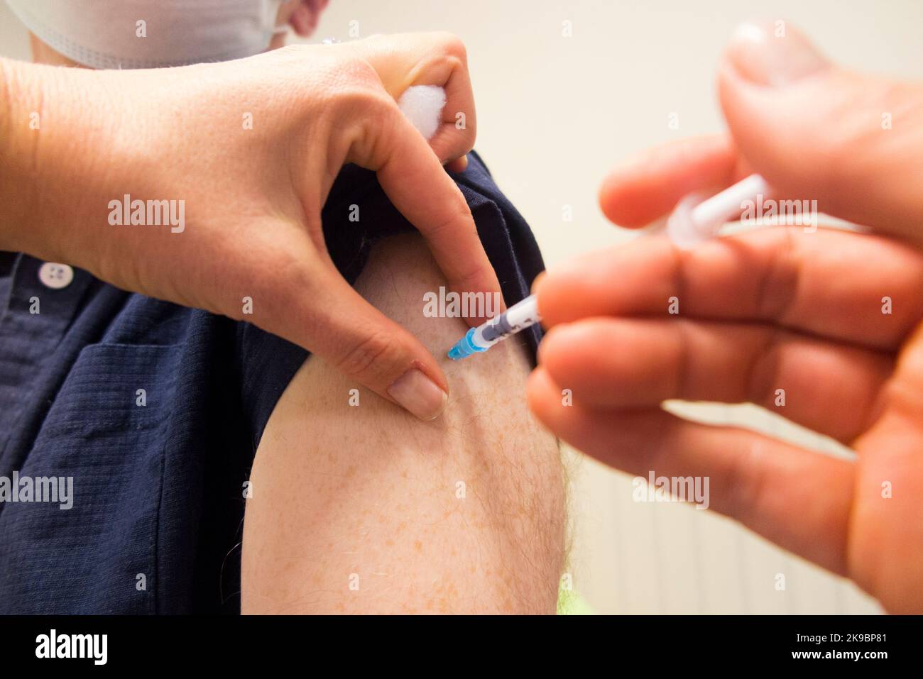 Mann im Alter von 59 Jahren (Model released) erhält den Impfstoff-Booster Pfizer COVID-19, um die Immunität zu verbessern und ihn gegen eine Infektion mit omicron Delta oder anderen vorhandenen Coronaviren einzuimpfen. Die Praxiskrankenschwester verwaltet die Injektion bei der örtlichen Hausarztpraxis in Twickenham. VEREINIGTES KÖNIGREICH (132) Stockfoto