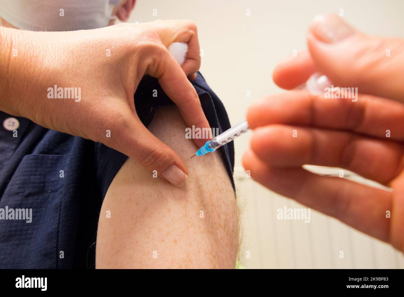 Mann im Alter von 59 Jahren (Model released) erhält den Impfstoff-Booster Pfizer COVID-19, um die Immunität zu verbessern und ihn gegen eine Infektion mit omicron Delta oder anderen vorhandenen Coronaviren einzuimpfen. Die Praxiskrankenschwester verwaltet die Injektion bei der örtlichen Hausarztpraxis in Twickenham. VEREINIGTES KÖNIGREICH (132) Stockfoto