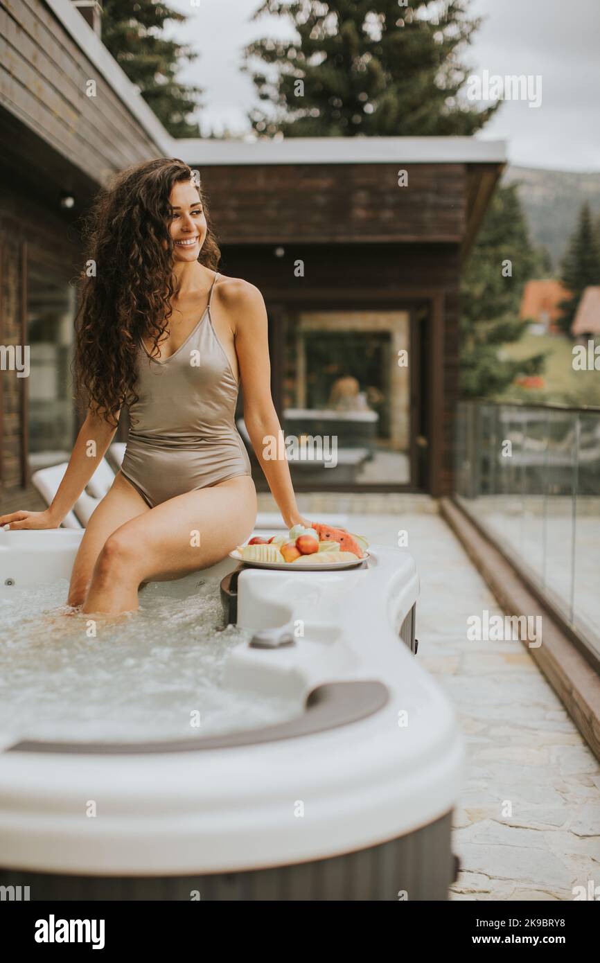 Attraktive junge Frau, die im Urlaub im Whirlpool im Freien genießt Stockfoto