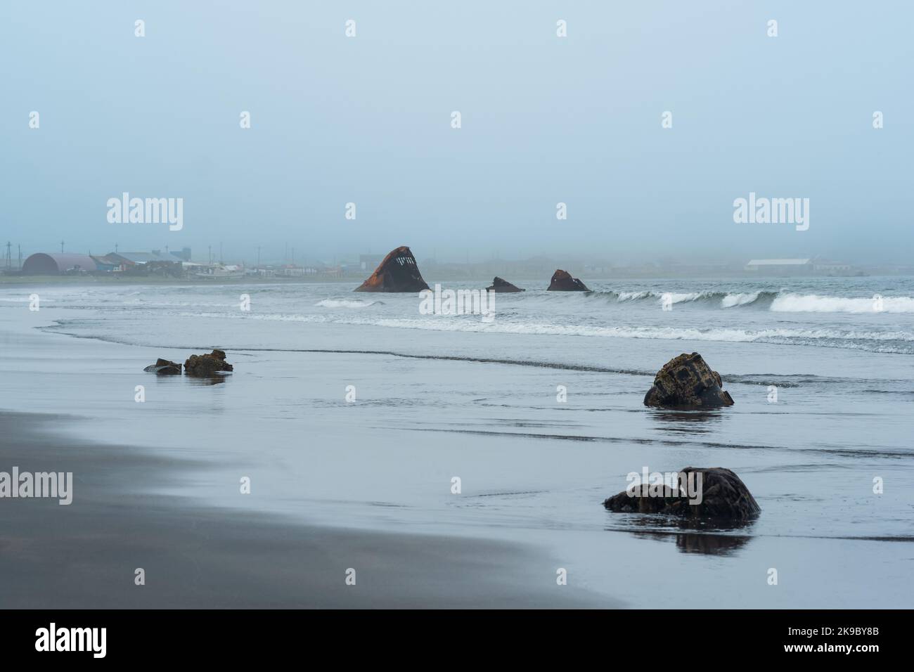 Neblige Küste der Insel Kunashir mit rostigen Schiffswracks während der Bewölkung Stockfoto